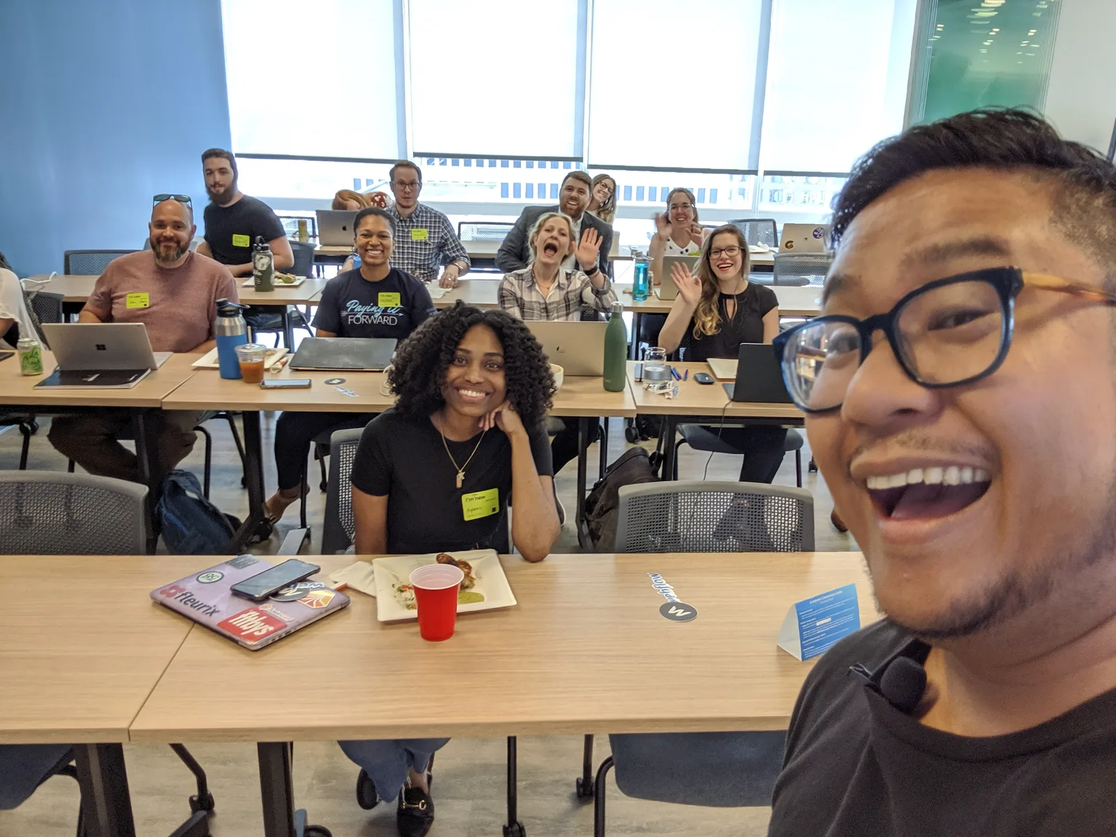 A room of workshop participants smiling toward a selfie camera